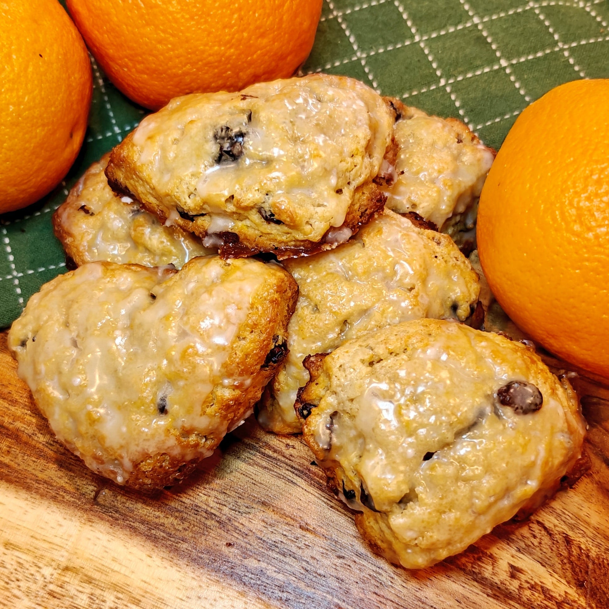 Orange Scones with glaze and cranberries on a wooden board with oranges