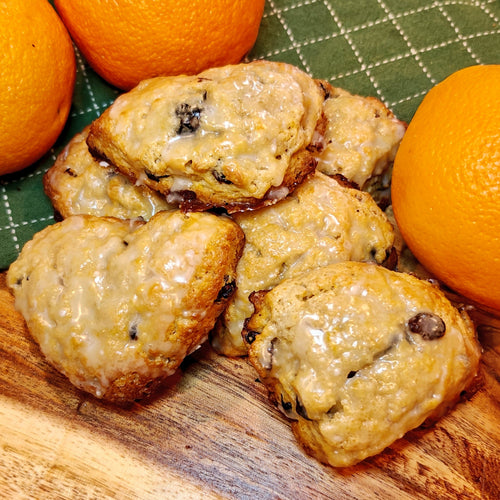 Orange Scones with glaze and cranberries on a wooden board with oranges