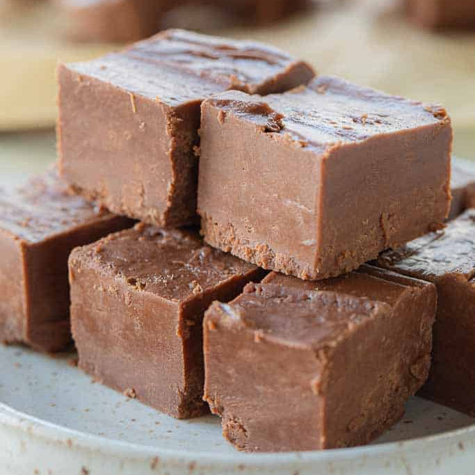 Chocolate fudge pieces stacked on a plate with a blurred background